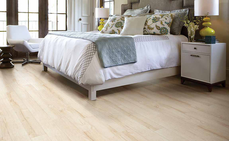 warm honey toned wood look laminate flooring in a bright bedroom
