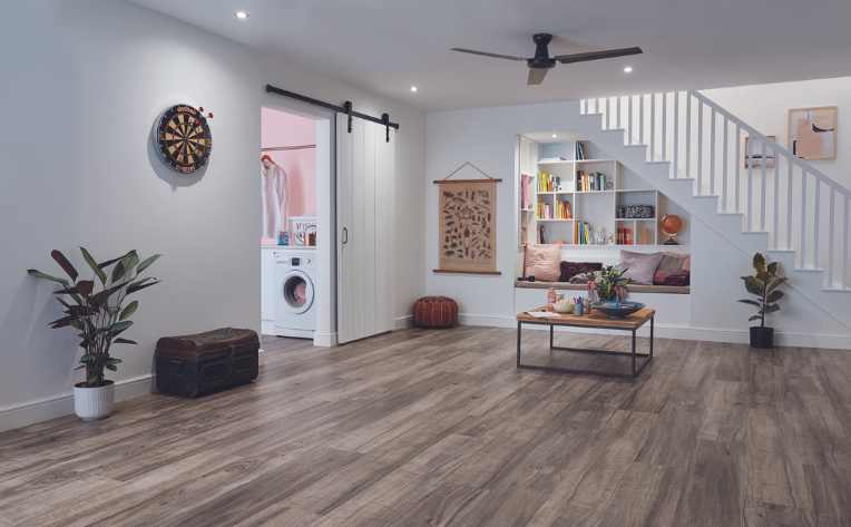 Cozy finished basement flooring with gray washed luxury vinyl and white barn door