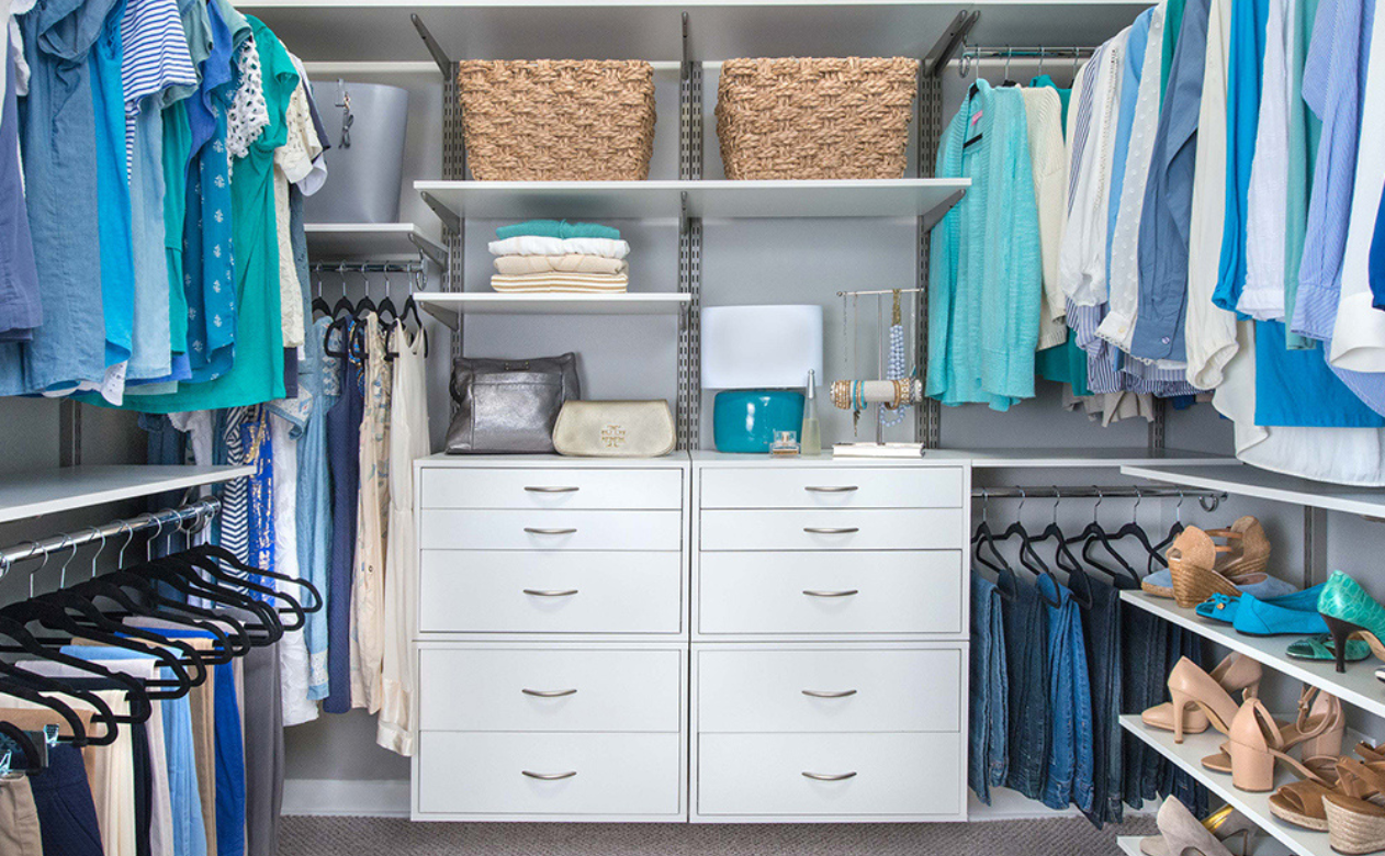 Organized walk-in closet with modular shelving, drawers, and hanging rods in neutral tones.