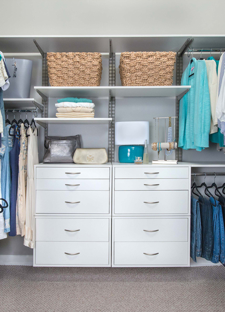 Organized walk-in closet with modular shelving, drawers, and hanging rods in neutral tones.