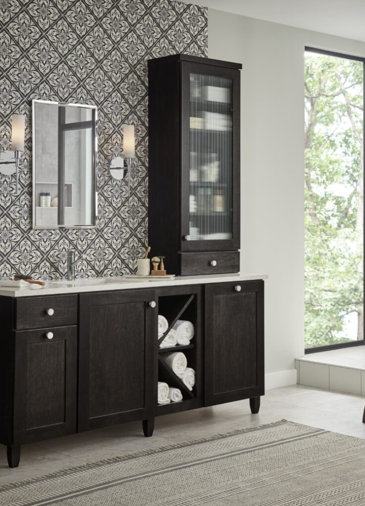 Dark wood vanity with a white countertop, patterned wallpaper, and chrome fixtures.
