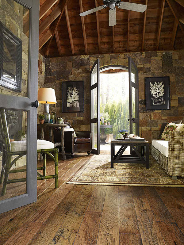Living room inside a rustic cabin with a wicker couch and area rug on the wood floor