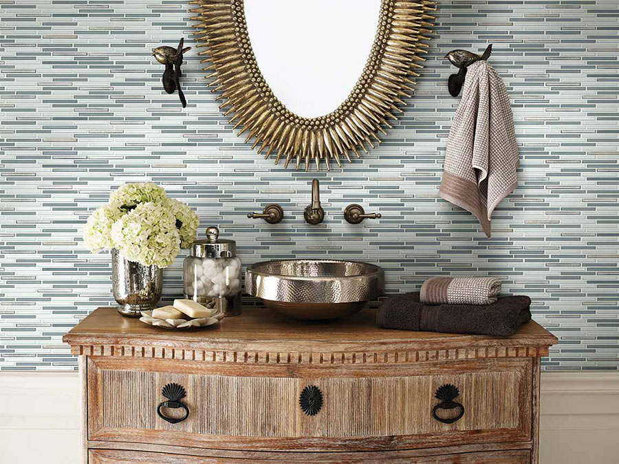 Close up image of a trending 2020 bathroom sink with a tile backsplash, bronze fixtures, and a mirror.