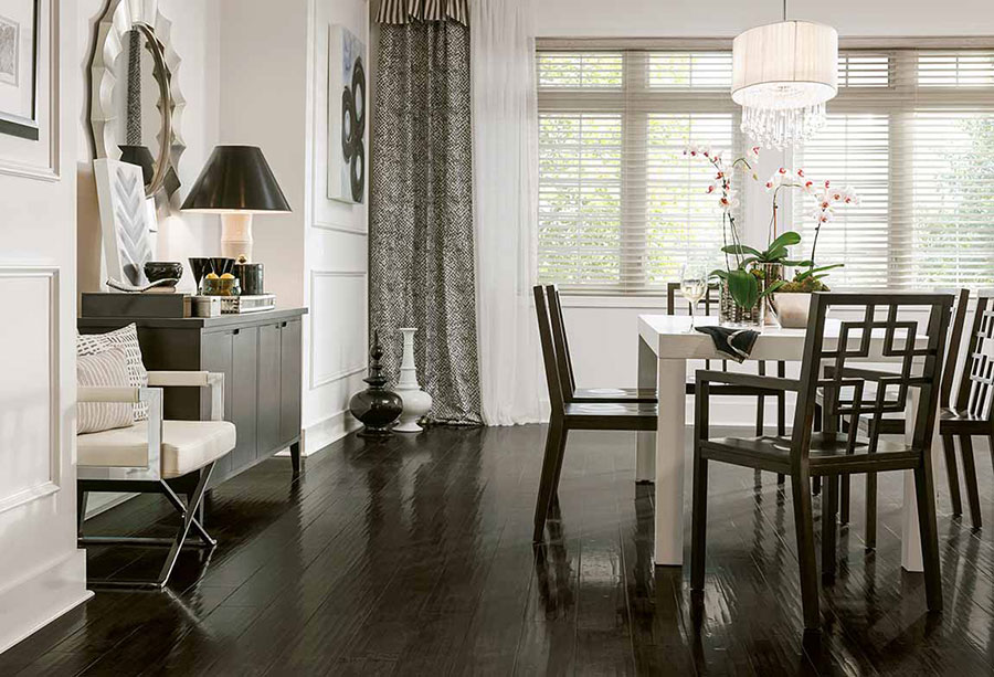 Dining room decorated with modern dining room decor on espresso wood floors and white and grey curtains covering windows. 