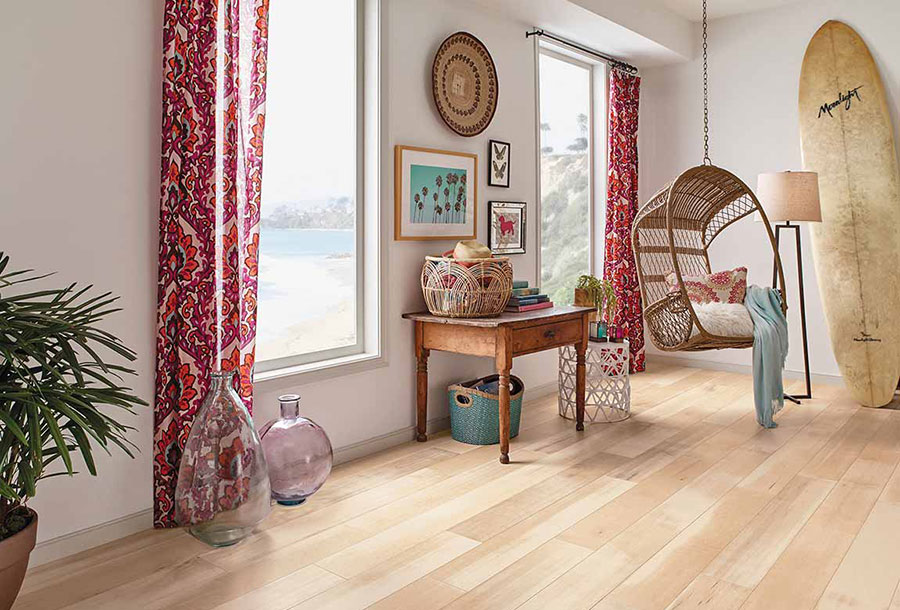 Coastal themed Living room with a hanging chair, surfboard and red floral print curtains on luxury vinyl plank floors.