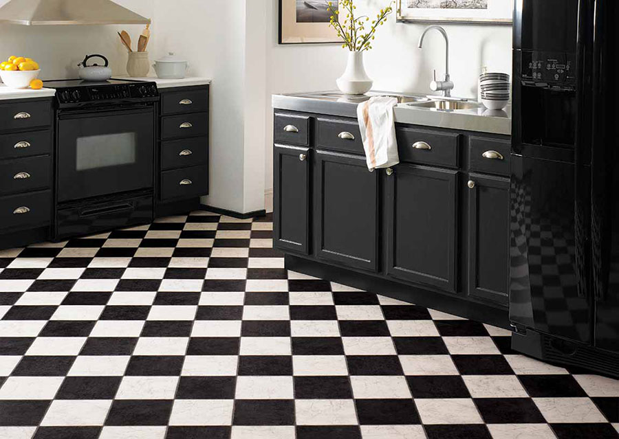 Kitchen with black cabinets and appliances on black and checkered floors, creating a high-end cafe feel.